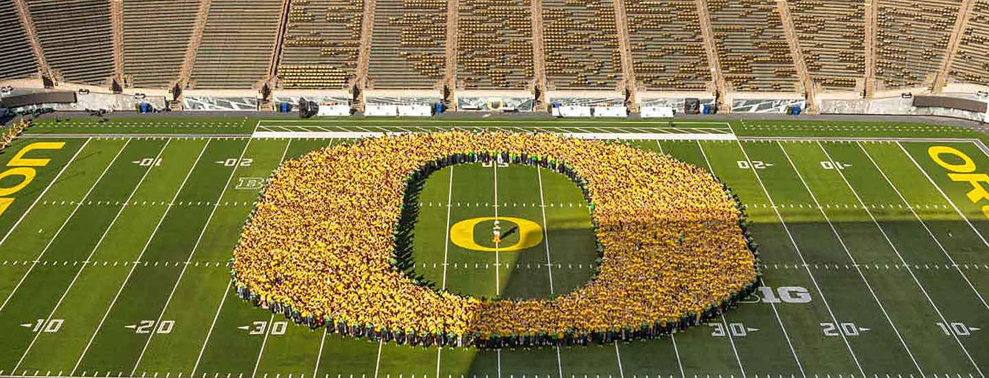 Students wearing yellow form an O on the field of Autzen Stadium