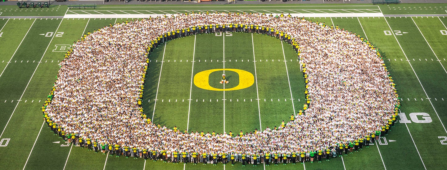 Students forming the UO "O" logo in the middle of a football field