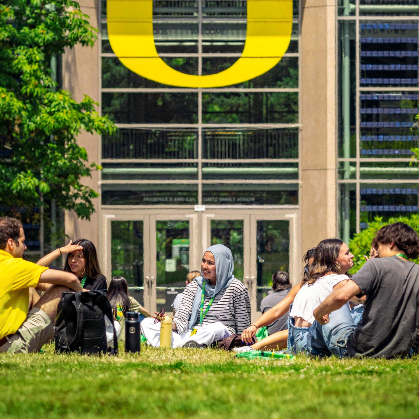 New students talking with a UO ambassador in front of a building showing a large "O" logo