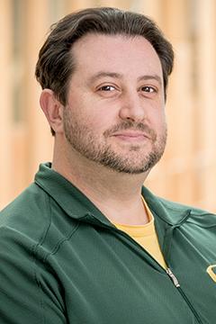 Profile photo of Joshua Puhn wearing a yellow shirt, and a UO-branded dark green cardigan