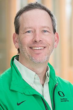 Profile photo of Michael Thompson wearing a light green button down shirt, and a dark green UO branded cardigan