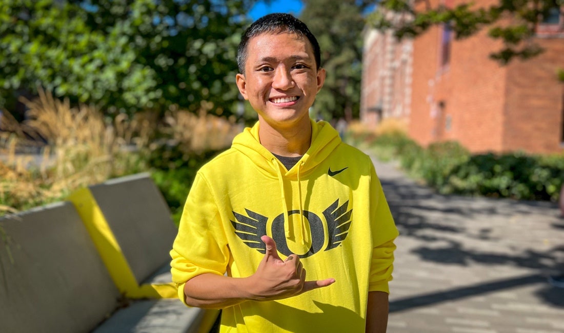 Maxwell Seguritan wearing a yellow hoodie with an Oregon "O" logo
